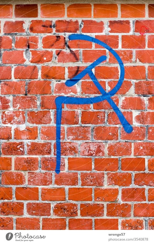 Hammer and sickle - a political symbol sprayed with blue paint on red brick hammer and sickle Symbols and metaphors Communism Politics and state Might Russia