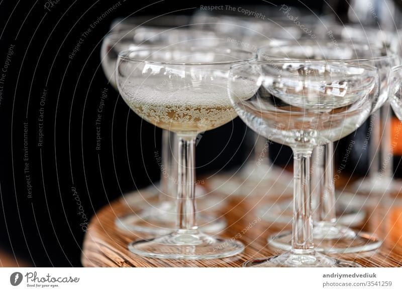 sparkling wine, champagne in glasses on the wooden table on black background in the restaurant. selective focus hand waitress catering group gloves open party