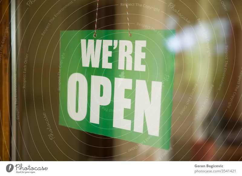 Open sign on the glass of the door at store advertising banner bar board business busy cafe city concept day entrance exterior front hanging hours information