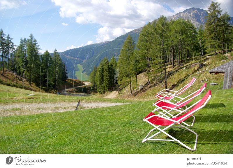 red deckchairs to rest hikers and admire the high mountains with meadows, woods and rocks benches sitting stone live beautiful light sun green tops sky clear