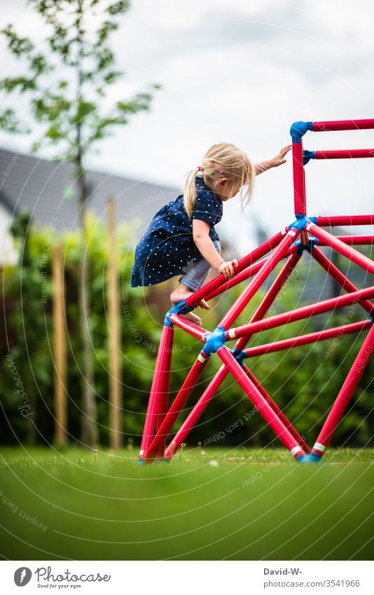 Girl climbing on a climbing frame in the garden girl climbs Climbing fun Joy courageous children Childlike Cute Playing Employment Garden toys Effortless