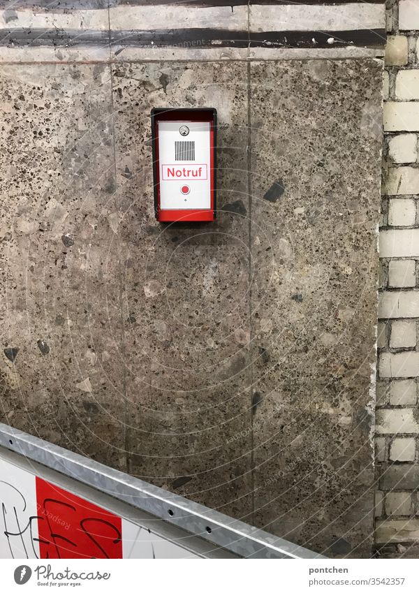 Emergency call system with red button mounted on a house facade. Danger, security, threat . Red knob Alarm Appliance Wall (building) Control barrier Striped
