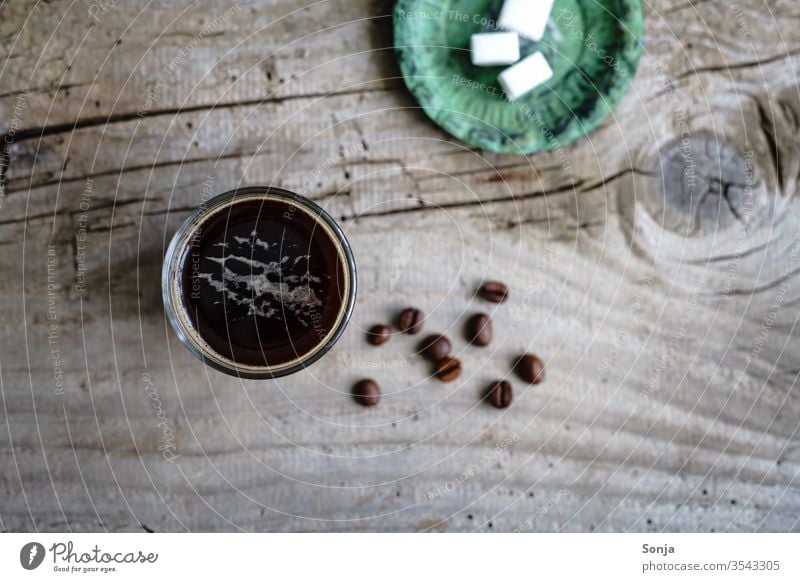 Coffee in a glass and sugar cubes on a green plate. Rustic wooden table, top view. Beverage Espresso glass cup Strong Aromatic Caffeine breakfast Wooden table