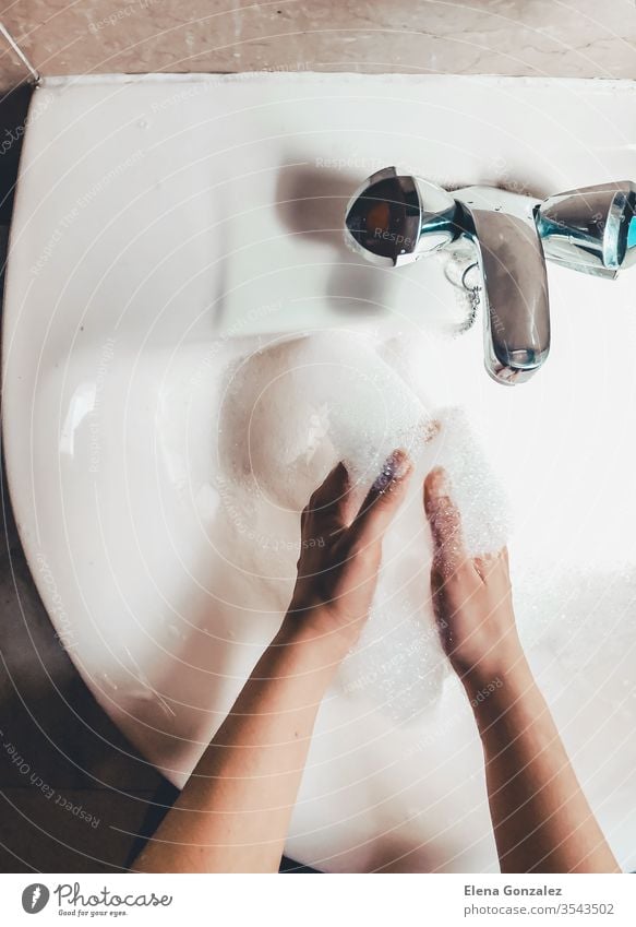 Woman washing her hands in bathroom to prevent Covid-19 infection. Recommended washing with soap and running water during coronavirus pandemic. Top view women