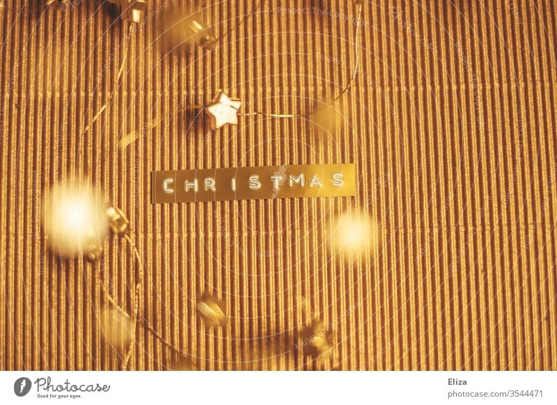 The word Christmas embossed on a gold label on a shimmering gold background with gold stars around it. Word Text merry christmas golden Label Christmas & Advent