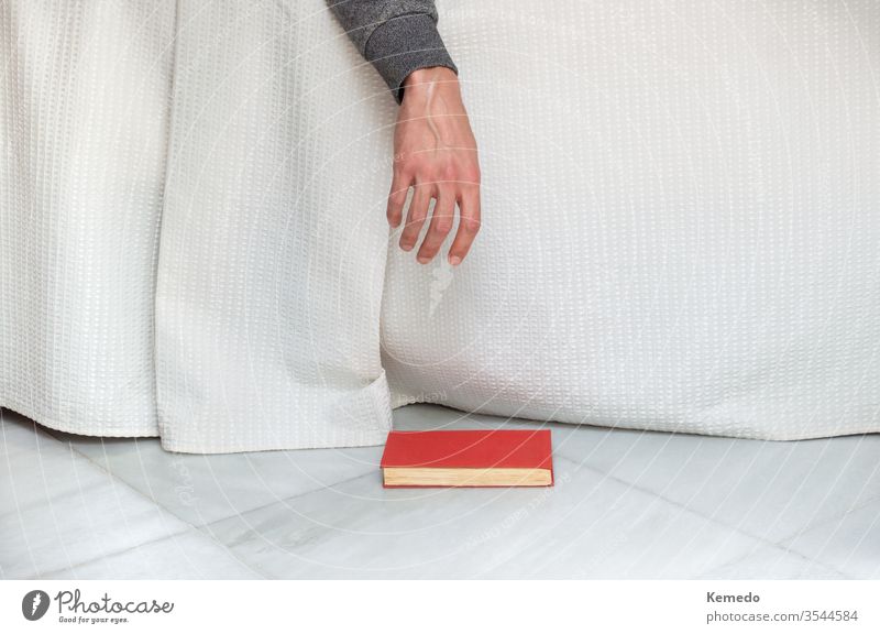 Person falls asleep while reading a book in bed and drops the book on the floor. Concept of boredom at home. person melancholy minimalist daydreamer people