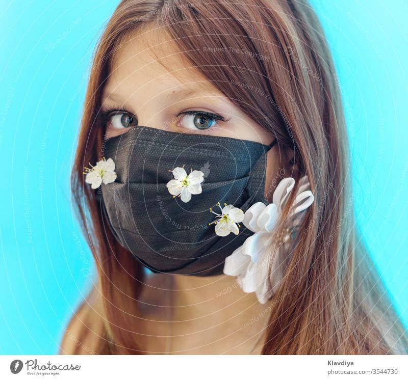 a girl in a black face mask decorated with flowers on a blue background beauty breathable care caucasian child cloth face covering colorful coronavirus covid