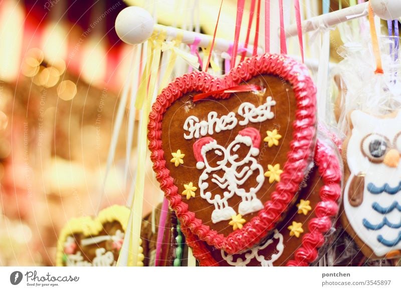 "Merry Christmas" is written on a gingerbread heart. Christmas. Christmas fair. Kitsch. Lights. Gingerbread heart Christmas Fair stand candy Tradition