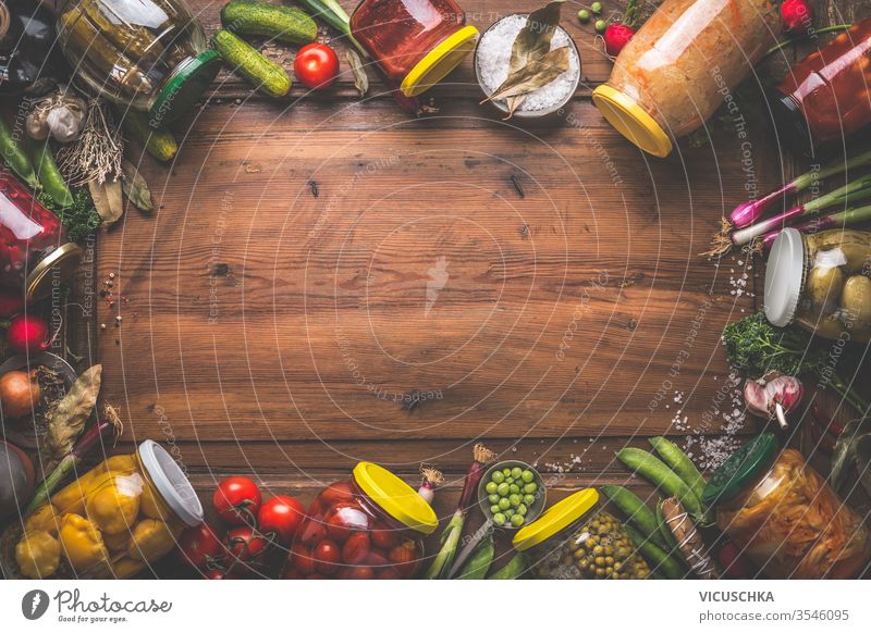 Wooden food background with various preserved vegetables in jars. Homemade harvest canning. Fermented vegetables. wooden fresh ingredients top view frame border