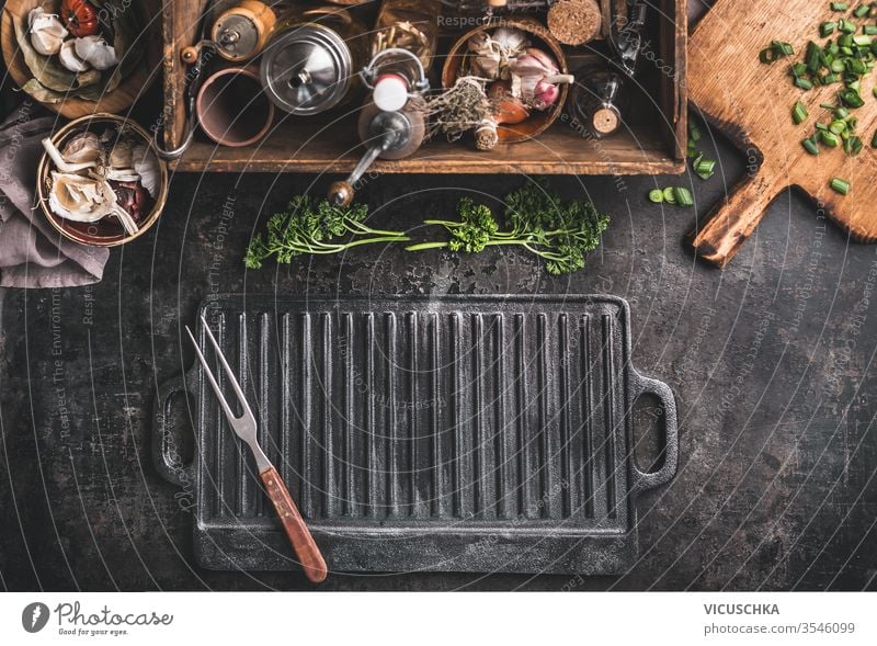 https://www.photocase.com/photos/3546099-grill-or-bbq-food-background-with-empty-cast-iron-grill-griddle-and-meat-fork-on-rustic-kitchen-table-wooden-box-with-seasonings-kitchen-utensils-dot-top-view-place-for-design-photocase-stock-photo-large.jpeg