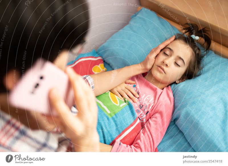 Mother worried about her daughter's temperature calling the doctor thermometer girl fever caucasian people care illness flu cold sick unwell sickness phone