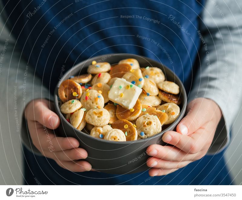 Pancake cereal in baby hands, copy space pancake cereal pancakes tiny pancakes mini pancakes child hold kid closeup sprinkles bowl food butter delicious recipe