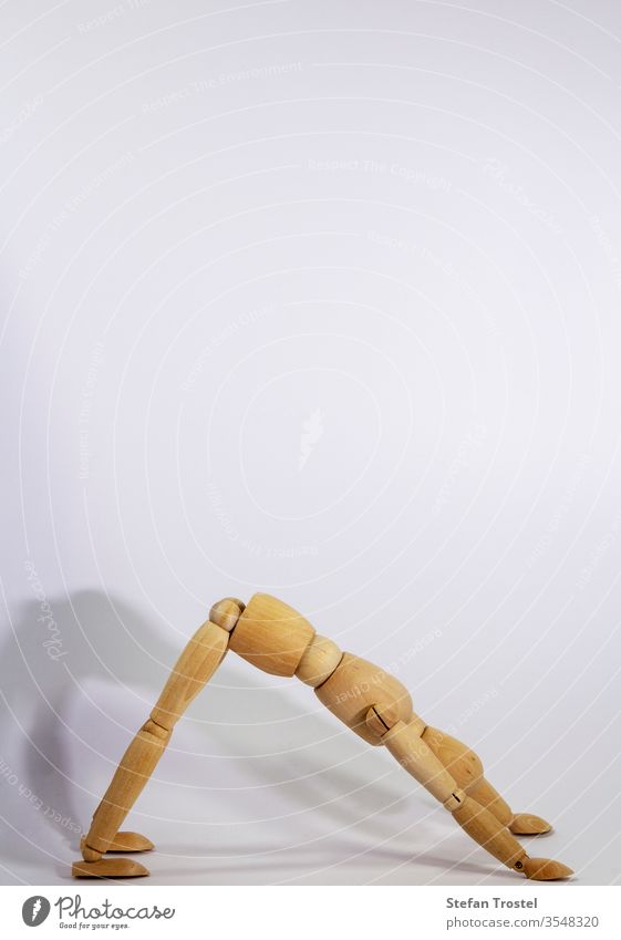 wooden doll during yoga practice Ansanas, looking down dog, in front of white background body dummy balance figurine fitness gesture sample model isolated