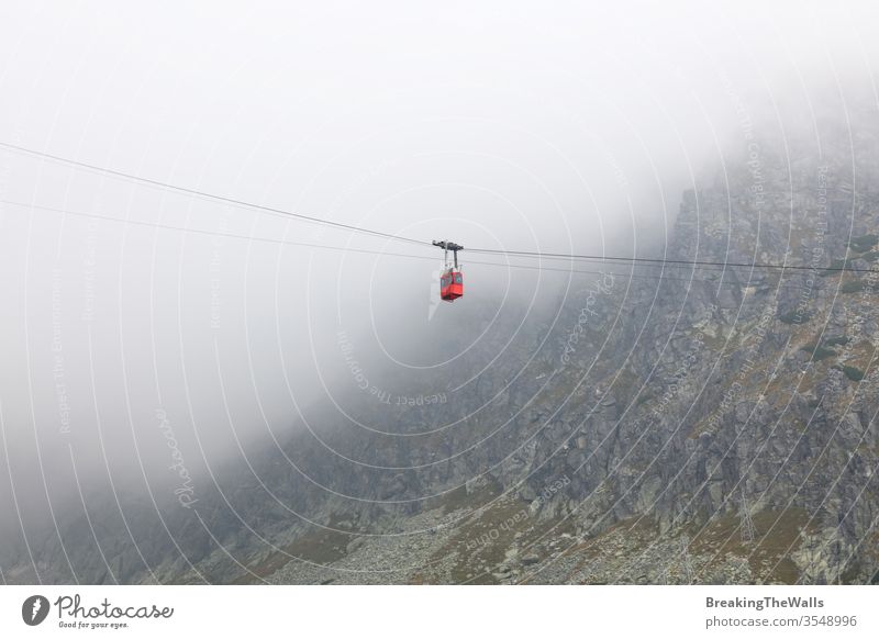 Red mountain cableway car lift in clouds and fog, low angle side view Cableway red landscape aerial ropeway airlift railway funicular cabin connection