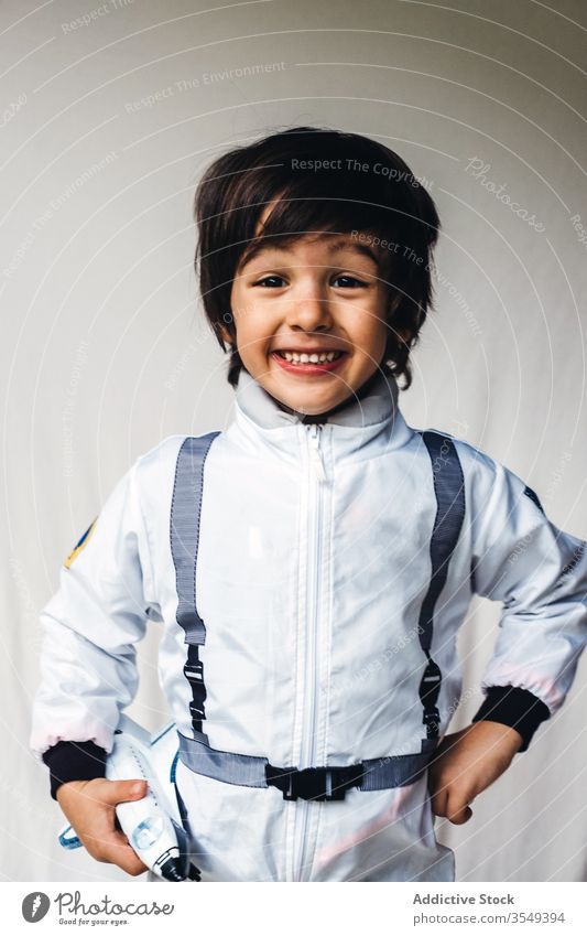 Adorable ethnic boy in cosmonaut costume on white background adorable spaceman toy spaceship positive child astronaut having fun kid spacesuit uniform smile