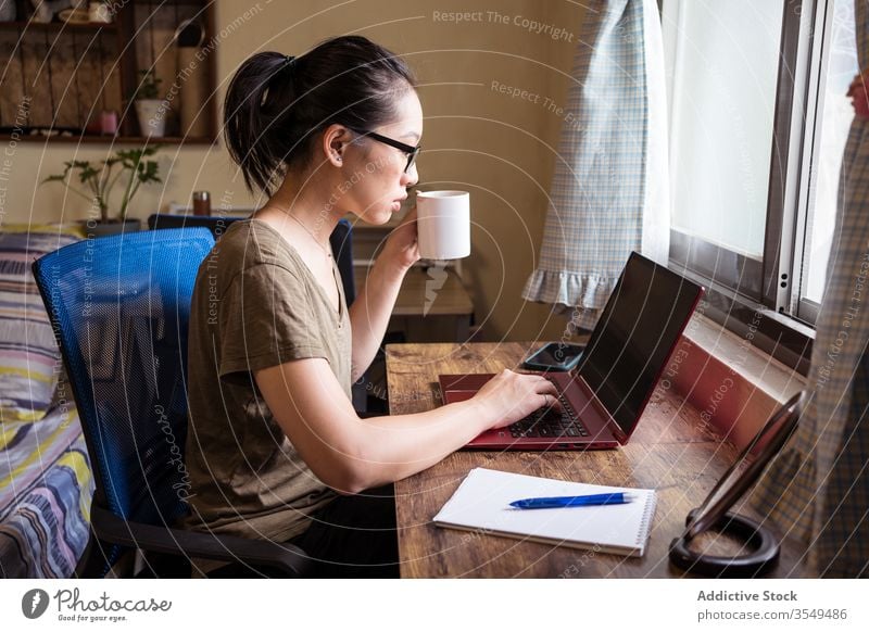 Busy female entrepreneur typing on laptop and drinking coffee woman home office busy using asian ethnic freelance concentrate self employed independent remote