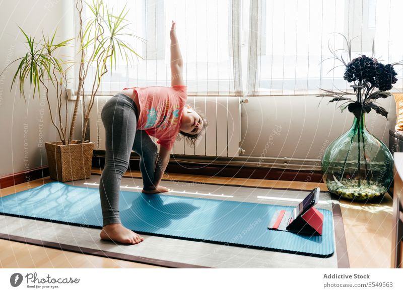 From above side view of little girl in casual sportswear performing Bridge  pose on mat while practicing yoga at home Stock Photo - Alamy