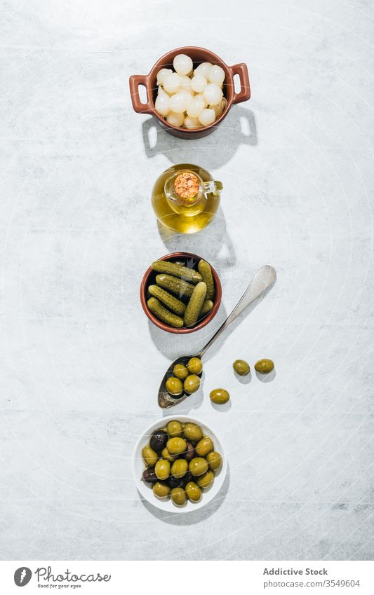 Bowls with snacks and glass jar with olive oil pickle bowl cucumber table row pickled extra virgin jug spoon kitchen plate dishware green cuisine gourmet