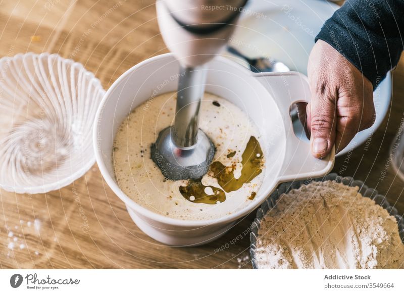 Pastry chef pouring flour into bowl to beat with blender Stock