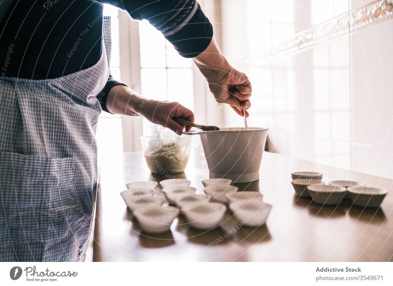 Aged woman mixing dough for muffins muffin case kitchen confectioner apron aged female cook prepare senior bowl plastic pastry process elderly make lady paper
