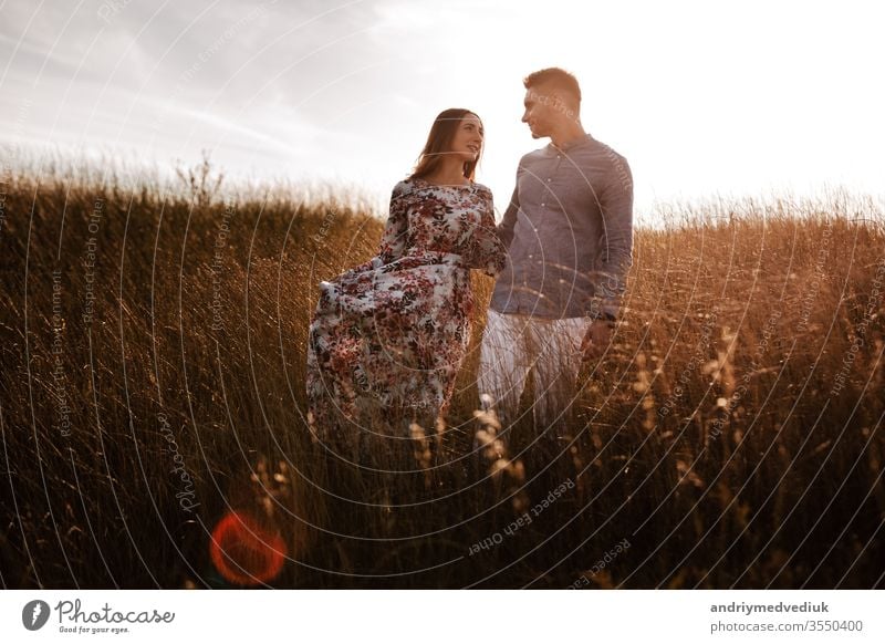 young couple resting in nature in a field. couple at sunset summer relationship man romantic love lifestyle landscape happy happiness people portrait girl