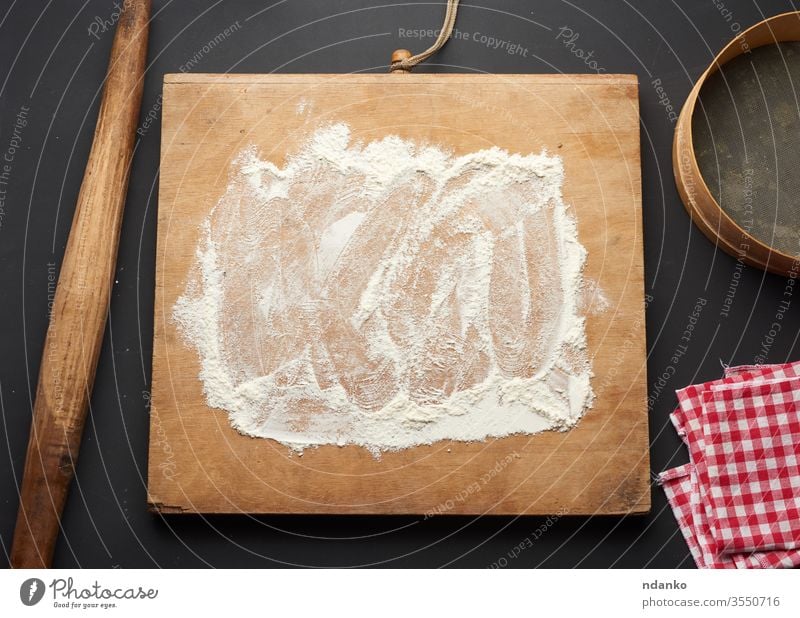 white wheat flour scattered on a black table and a wooden rolling pin dough food fresh freshness grain home bake abstract background bakery board bread brown