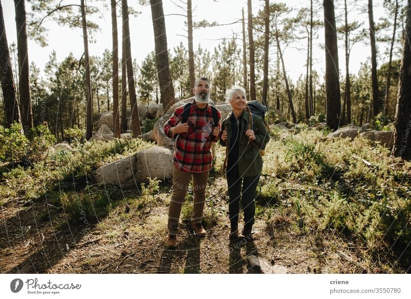 Elferly fit happy couple hiking through forest together on vacation man senior elderly rock nature outdoors hike sport lifestyle activity hiker active people