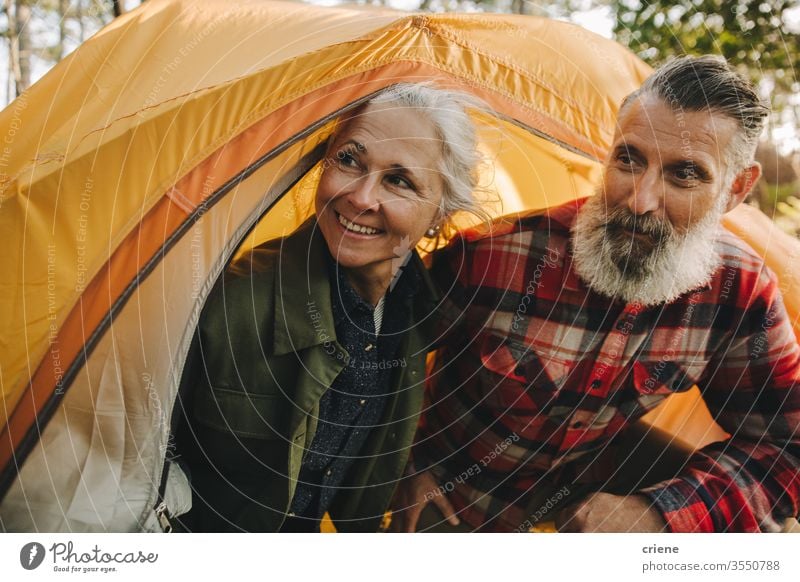 Happy senior couple looking outside yellow tent smiling smile happy enjoying active activity tourist leisure holiday seniors travel backpack nature hiking love