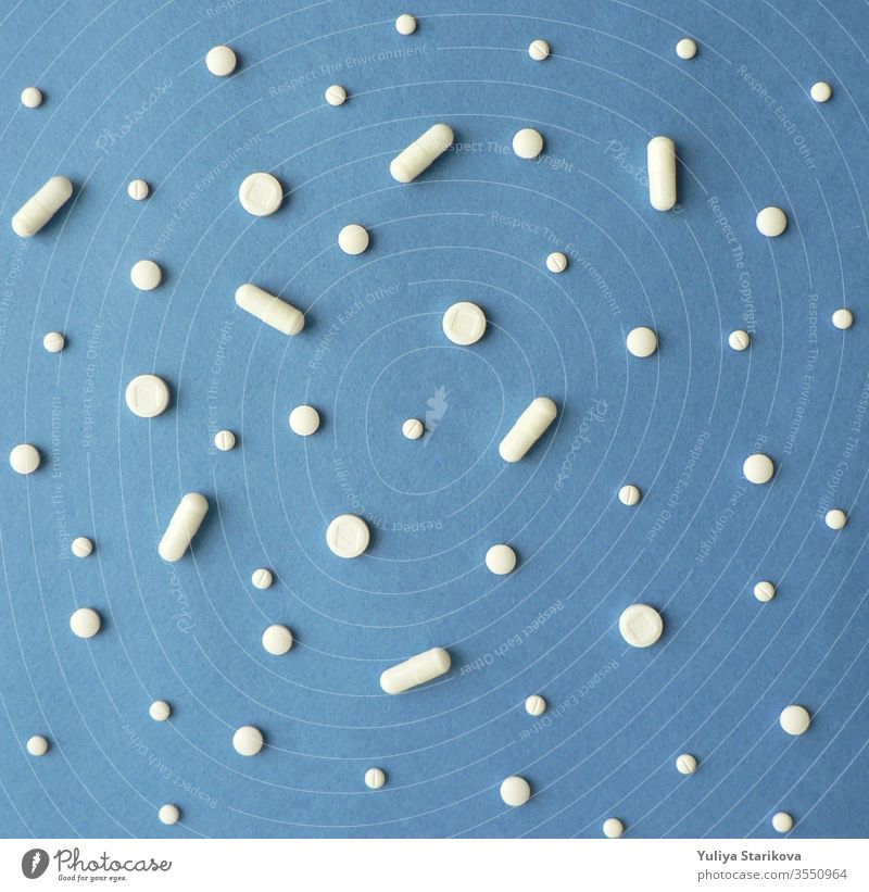 Creative scandinavian style flat lay top view of white pills and capsules on a blue background. Treatment and of hope for recovery. Creative idea for drugstore, online pharmacy, health lifestyle and pharmaceutical company business concept.