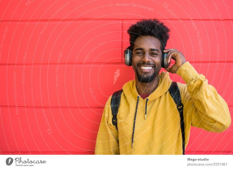 Young afro man listening to music with headphones. earphones happy sound background adult modern young friendly media expression cool in-ear earbud portable