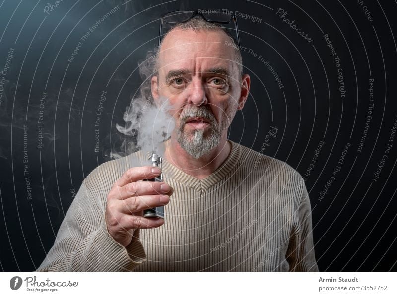 portrait of a man with beard who is vaping background blowing blur cigarette cigarettes confident cool e-cigarette ecig electronic equipment exhaling gray hand