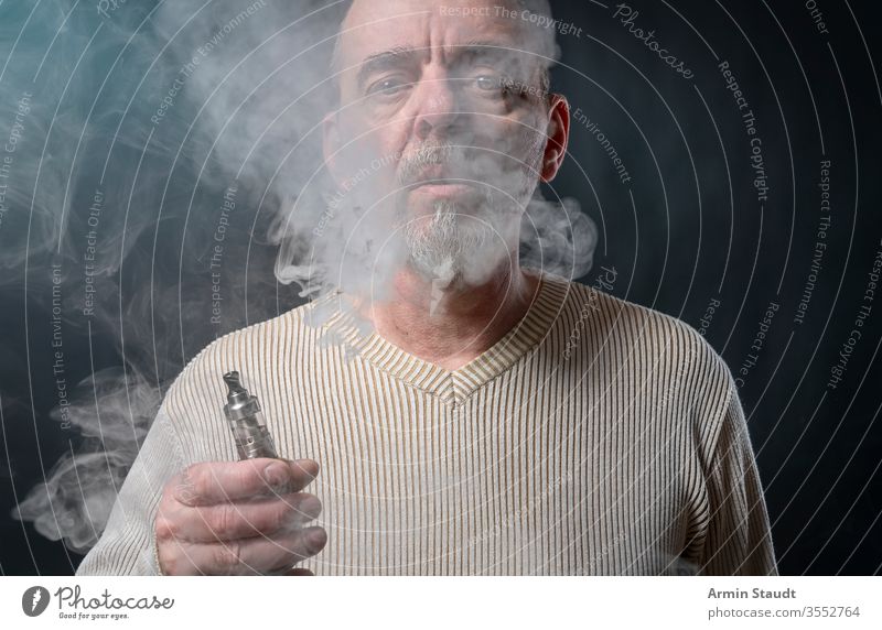 portrait of a man with beard who is vaping background blowing blur cigarette cigarettes cool e-cigarette ecig electronic equipment exhaling gray hand health