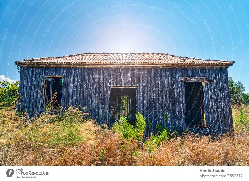 old abandoned wooden cottage with the sun behind damaged empty idyllic greece nature countryside architecture barn blue broken building corrugated environment