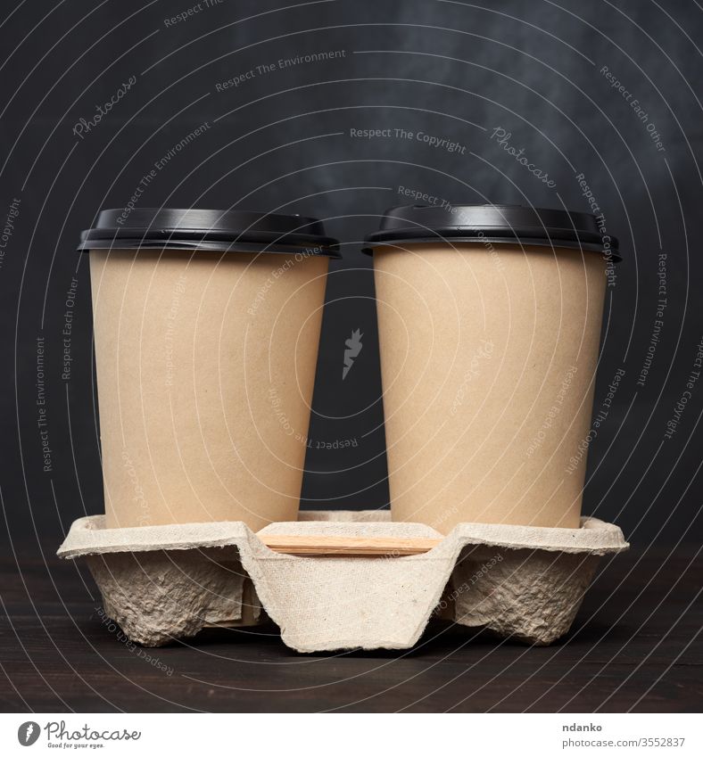 two brown paper disposable cups with a plastic lid stand in the tray on a wooden table container cover drink empty americano background beverage black blank