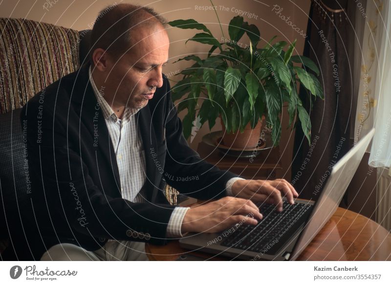 Serious adult male working from home typing by laptop with plant on backgroung work from home senior man telework computer online social life isolation distance