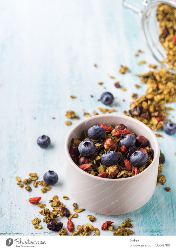 Home made matcha green tea granola in bowl. berries oatmeal healthy plant based homemade breakfast cereal chestnut concept cranberries background blue diet