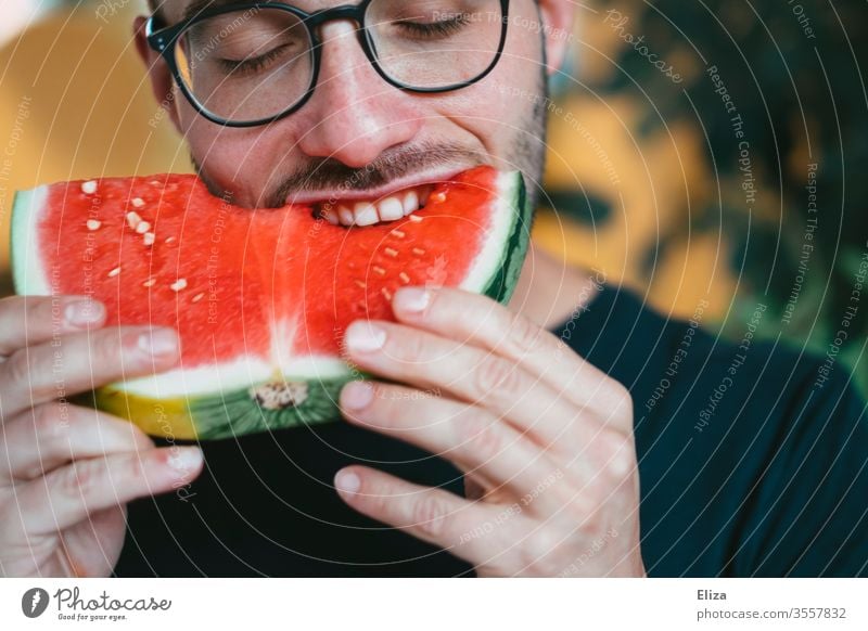 A man bites into a piece of watermelon Water melon bite into Bite Delicious Eating smile salubriously Fruity Man Joy feast fruit Juicy nib Nutrition Red Healthy