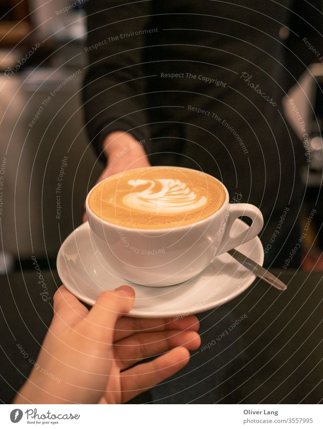 A cafe latte with swan latte art being handed from barista to customer Coffee Coffee cup coffee culture coffee shop coffee house flat white Caffeine