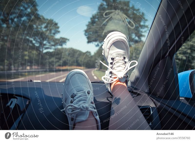 Freedom car travel concept - woman relaxing with feet on dashboard wearing white sneakers. Sexy woman in the car. background fashion tree person girl couple