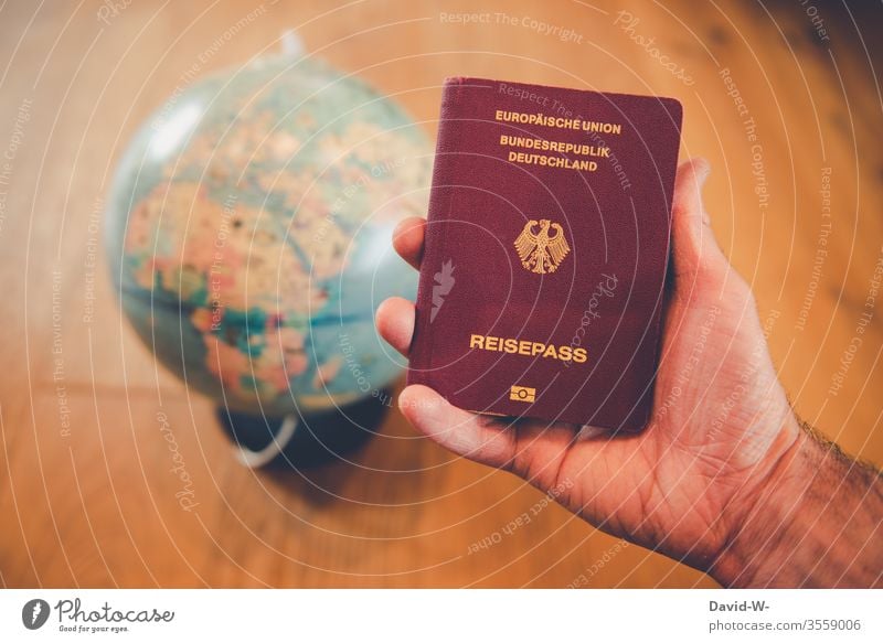 World trip - man holding passport in his hand with globe in the background Travel pass vacation Globe Around-the-world trip go away Man by hand Human being