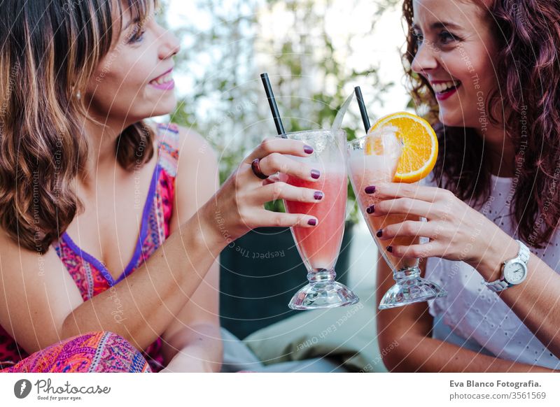 two friends enjoying a healthy smoothie in a terrace. summer time and friendship women happy juice fruit iced green sweet caffeine natural drink beverage