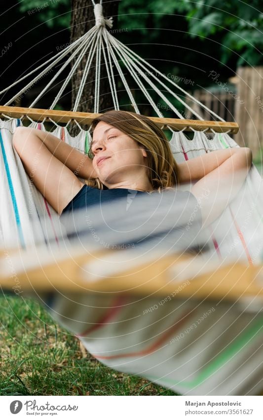 Young woman relaxing in the hammock in nature adult alone backyard calm carefree casual comfortable countryside day dream easy enjoy female forest furniture