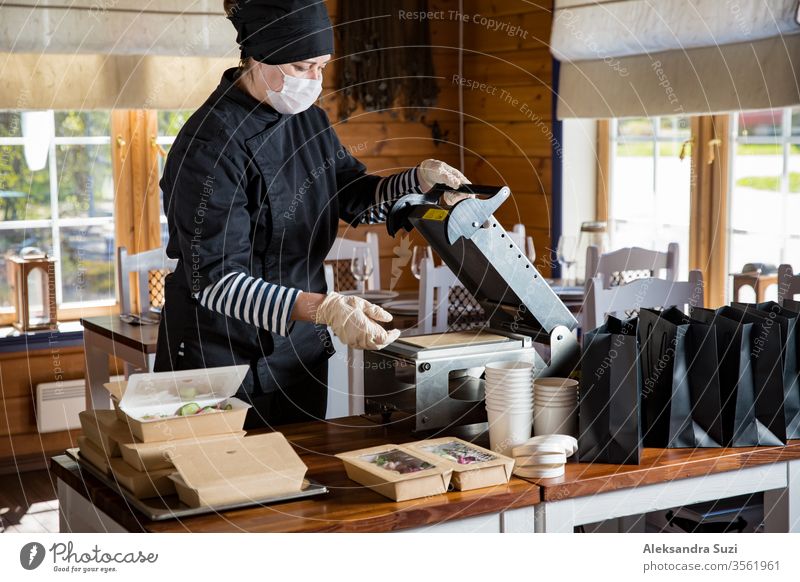 Restaurant worker wearing protective mask and gloves packing food boxed take away. Food delivery services and Online contactless food shopping. business buy