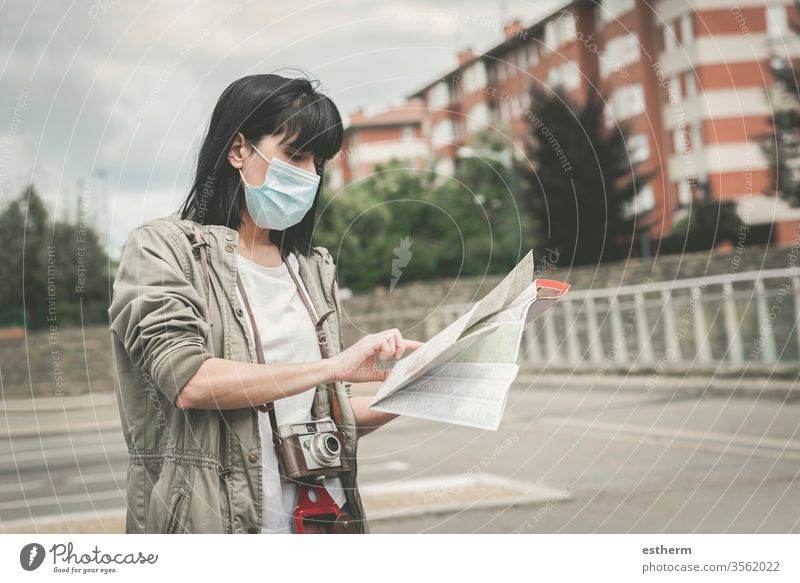 woman wearing medical mask with a camera look at a map of the city coronavirus young woman epidemic traveler traveling tourist tourism holidays pandemic
