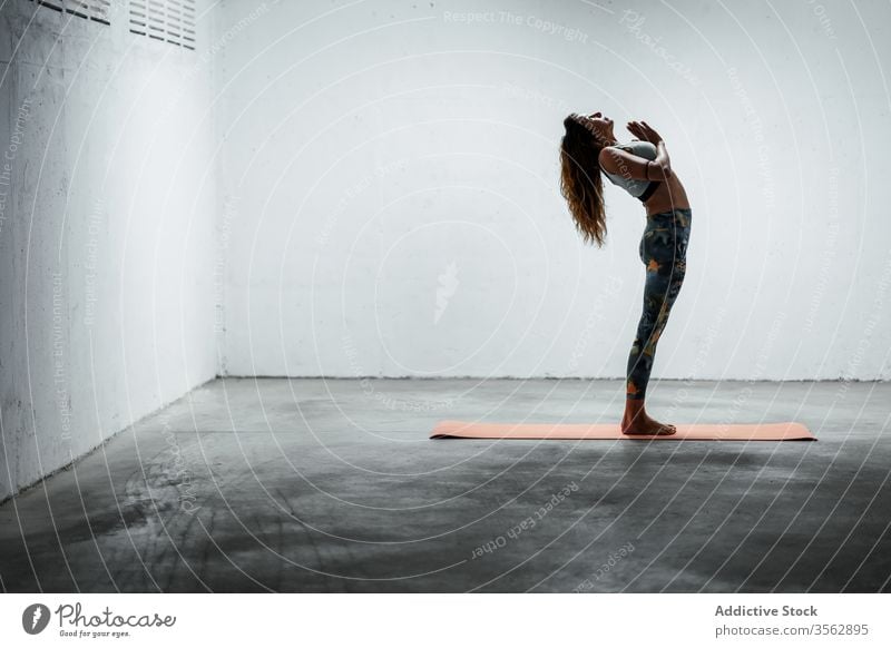 Slender woman doing yoga in Mountain pose with raised arm balance practice calm standing backbend slender asana female slim mat flexible floor sportswear