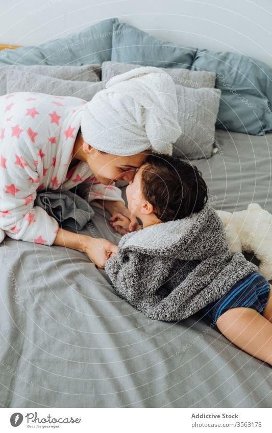 Mother playing with son in bedroom mother having fun bathrobe content game pastime little boy parent parenthood mom motherhood childhood kid adorable cute lying