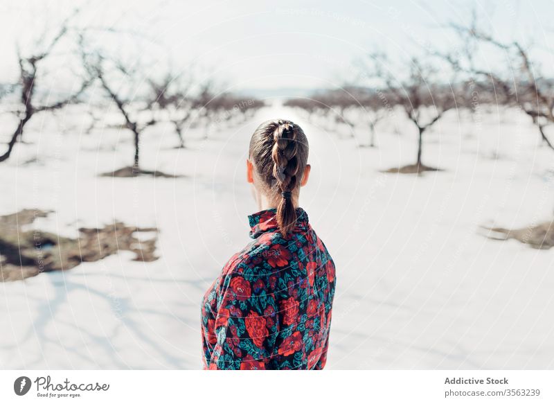 Anonymous woman standing in snowy field style trendy confident nature braid attractive modern fashion charming colorful defiant red young sensual outfit