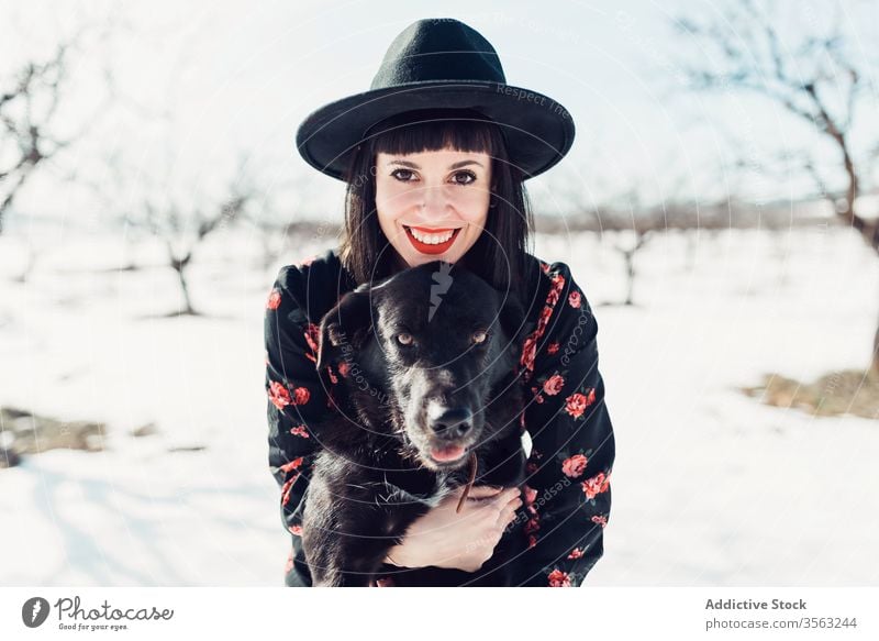 Stylish woman with dog in winter field style trendy snow black together pet female fashion park relax forest tree calm hat breed cold sun owner beautiful cloth