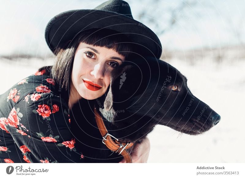 Stylish woman with dog in winter field style trendy snow black together pet female fashion park relax forest tree calm hat breed cold sun owner beautiful cloth