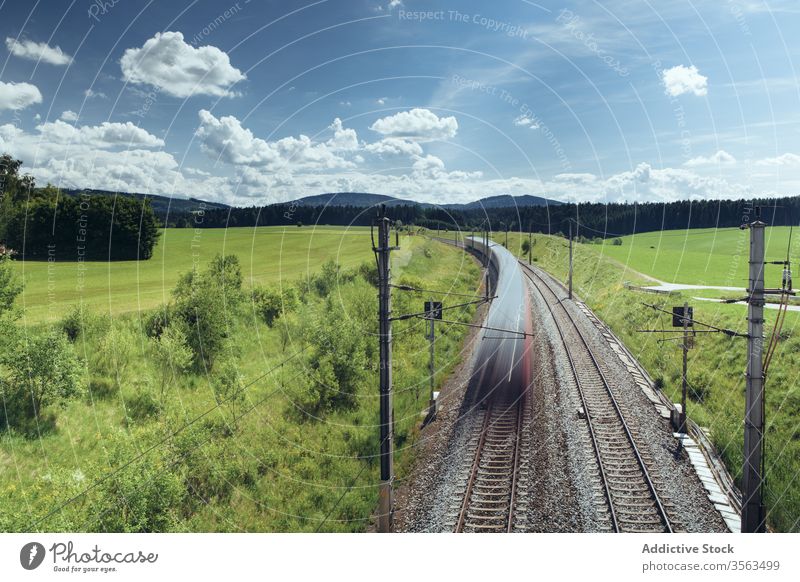 Picturesque scenery of fast train on railway ride railroad landscape field mountain long exposure majestic picturesque green sunny nature transport speed motion